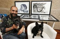 Marcos M�guez Puhinger, con su perra Pepa en su regazo y al lado el hijo de esta, Lomu, rodeados por algunos de sus dibujos. 