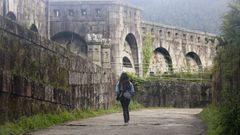Una persona camina por la carretera llena de baches que rodea el muro del castillo de La Palma. 