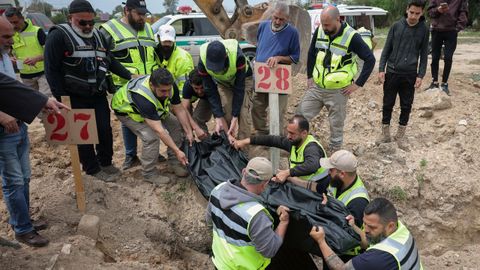 Personal de defensa civil baja el cuerpo de una joven de 19 a&ntilde;os, muerta en un bombardeo israel&iacute; en Trio, a una tumba provisional.