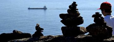 Un ni�o observa la entrada de un mercante en la r�a junto a tres peque�os mont�culos de piedras.
