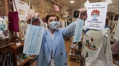 Teresa Rodr�guez, con las mascarillas que ofrece a la clientela y el cartel donde informa de que hay que llevarla para entrar en sus dos negocios. 