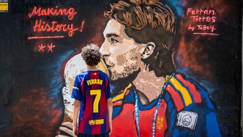 Un ni�o, con la camiseta del Bar�a de Ferran Torres, observa el mural pintado en la Ciudad Condal en honor al goleador del Mundial.