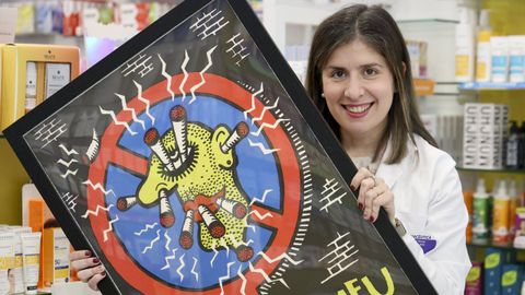 Noa Rey Torres muestra un cartel antitabaco en la farmacia de la que es titular, en la calle Real de Pontedeume
