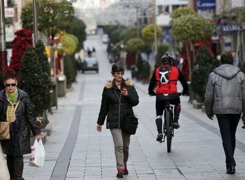 Tres usuarias buscan cobertura de wifi en la calle peatonal de O Calvario