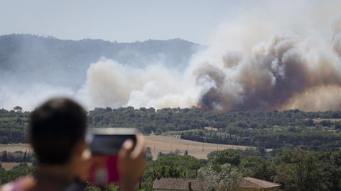 Un hombre observa, durante la tarde de este viernes, la columna de humo del incendio forestal que se ha declarado en La Bisbal del Ampurd�n (Girona)