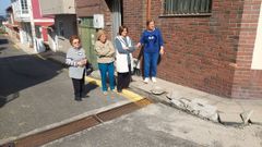 Un grupo de vecinas junto a la acera destrozada por los coches.