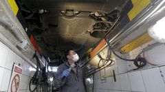 Un inspector examinando los bajos de un coche en la ITV