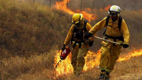 Dos bomberos cargados con sus herramientas durante los incendios de Lower Lake, en California