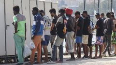 Varios migrantes esperando para acceder al aseo este mi�rcoles en la playa ceut� de El Trampol�n.