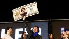 Milei eleva un billete de cien d�lares con su cara, en una imagen de archivo.