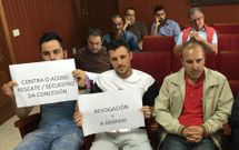 Trabajadores muestran carteles cr�ticos con sus jefes sentados al fondo del sal�n de plenos. 