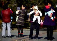 Varias mujeres sujetan en brazos a sus respectivos beb�s en un c�ntrico parque de Pek�n.