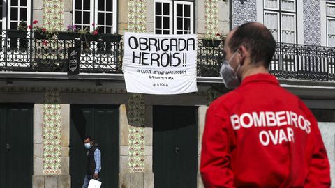 Un bombero, frente a una vivienda con una pancarta de agredecimiento en la localidad de Aveiro