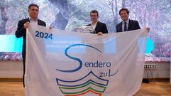 El concejal de Medio Ambiente de Sanxenxo, Juan Deza, en el centro, posa con la bandera del programa senderos azules