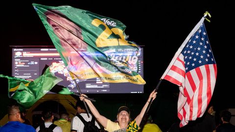 Una seguidora de Fl�vio Bolsonaro sostiene una bandera del candidato de ultraderecha y otra de Estados Unidos, durante la jornada electoral, en Brasilia