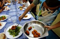 Un alumno, sirviendo un plato del men� en el comedor de un centro escolar.