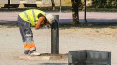 Un operario se refresca en una fuente por las altas temperaturas en un parque de L�rida.