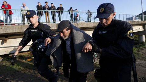 Dos policas ayudan a un refugiado en Brezice, Eslovenia