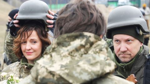 Lesia Ivashchenko y Valerii Fylymonov escuchan a un sacerdote en su boda durante el conflicto Ucrania-Rusia, en un puesto de control en Kiev, Ucrania.