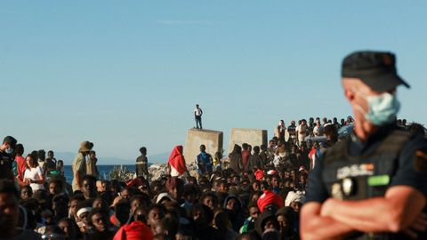 Los migrantes hacen fila para recibir alimentos y bebidas de la Cruz Roja.