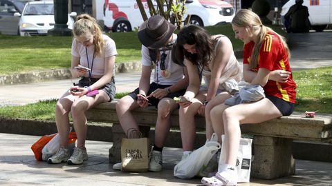 En Santiago de Compostela el dio se mantuvo despejado. En la fotografía, jóvenes toman el sol en un banco de la Alameda.
