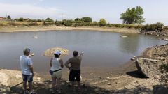 Vecinos de Cerceda muestran el lago desde donde captan el agua de la tra&iacute;da, casi seco.