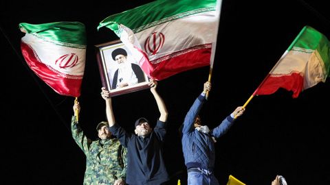 Un grupo de fieles al r�gimen sujeta en alto un retrato del ayatol� y las ense�as nacionales