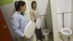 Nuria Otero y Vanessa Higuera, con las tapas de protesta y ante los baos sin puertas.