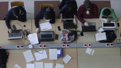 Alumnos con ordenadores y apuntes a mano en la facultad de Informtica de Elvia