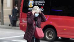 Una mujer con mascarilla se pone un sombrero en una calle del centro de Monforte