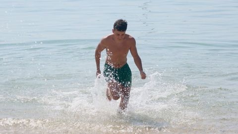 Un bañista sale corriendo del agua en la playa de Coroso