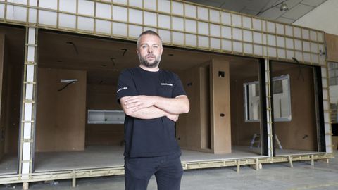 Álvaro Aneiros en la nave del polígono de A Xunqueira donde tiene el taller, con una casa en fase de montaje detrás