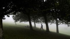 Un hombre camina entre la niebla en el Monte Naranco de Oviedo.