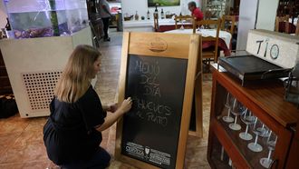 La camarera del restaurante Tío Pepe, en Ribeira, ayer, escribiendo en la pizarra el menú del día.