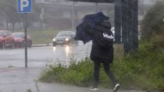 Una joven intenta en la zona del campus de Lugo que el viento y la lluvia no se lleven su paraguas