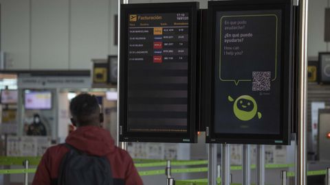 En una imagen de archivo, un panel de información de vuelos y el control de pasajeros en el aeropuerto Rosalía de Castro de Santiago