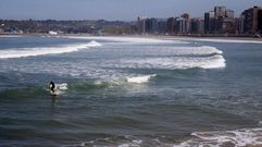 Un surfista disfruta del buen tiempo en la playa de San Lorenzo, en Gij�n
