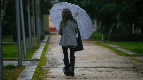 Una mujer camina bajo la lluvia  en Noia