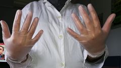 Una trabajadora del servicio de ayuda a domicilio muestra su equipo de protecci�n, unos guantes y una bata de tela
