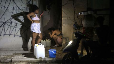 Persoas enchen recipientes con auga durante un apag�n o xoves pasado na Habana