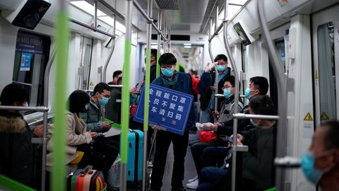 Un miembro de la empresa muestra un cartel que dice: Llevar siempre mascarilla, evitar aglomeraciones y mostrar el código para escanear al salir del tren .