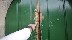 Puerta destrozada a golpes por los ladrones que entraron en la iglesia de Bord�ns