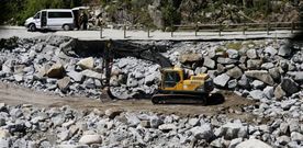 Una excavadora trabaja sobre el terreno para recolocar las grandes rocas desplazadas por el agua hace tres meses. 