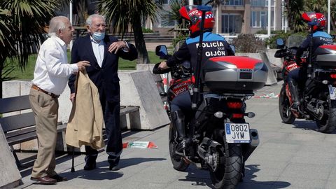 Agentes de la polica local advierten a dos personas mayores que no pueden utilizar los bancos pblicos para sentarse en Gijn, este mircoles durante el tercer da de la fase 0 de la desescalada. 