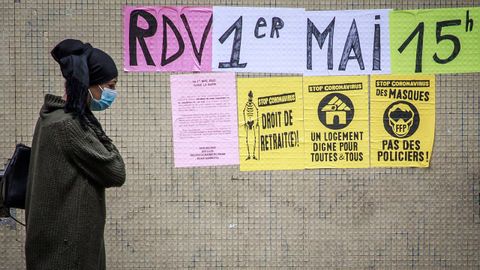 Una mujer pasea por una calle de Par�s, entre mensajes de protesta por la gesti�n de la crisis sanitaria y los carteles de un Primero de Mayo que no pudo ser celebrado