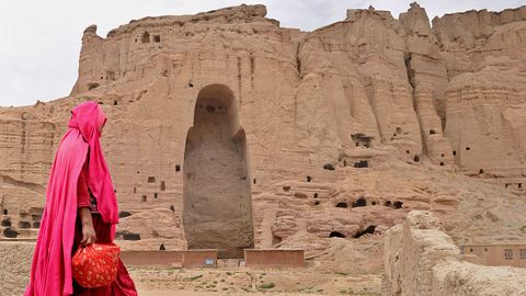 Una mujer pasa frente a las ruinas de una estatua gigante dedicada a Buda