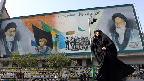 Unas personas pasan frente a un mural que representa al difunto l�der de la Revoluci�n Isl�mica, el ayatol� Ruhollah Jomeini, y al difunto L�der Supremo de Ir�n, el ayatol� Al� Jamene�.