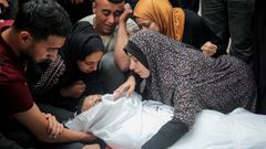 Varios gazatíes lloran alrededor de un cuerpo, durante un funeral en Rafah.