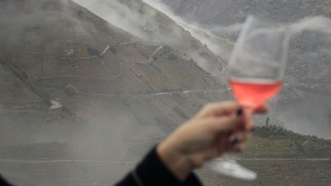 En la foto, una persona sostiene una copa de vino�ante un paisaje en la zona de�Monforte