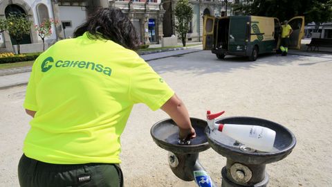 Una operaria procede al arreglo de una de las fuentes de la Praza Maior